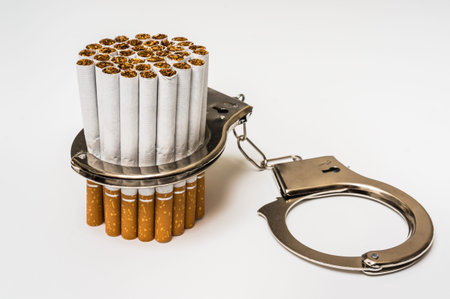 Cigarettes and handcuffs - smoking addiction concept on white backgroundの写真素材