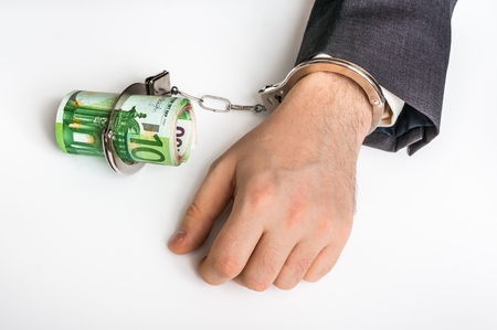 Man in suit chained with handcuffs to money - corruption conceptの写真素材
