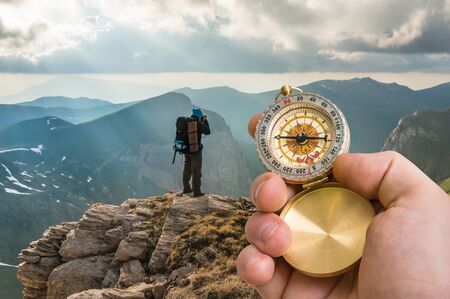 Traveler man with compass seeking a right way in the mountains - navigation conceptの写真素材