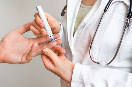Measuring blood sugar on finger - diabetes and glicemia conceptの写真素材