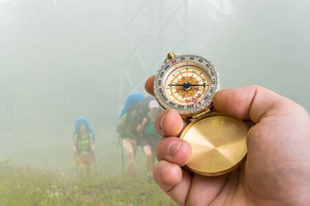 Traveler man with compass seeking a right way through the fog in mountains - navigation conceptの写真素材