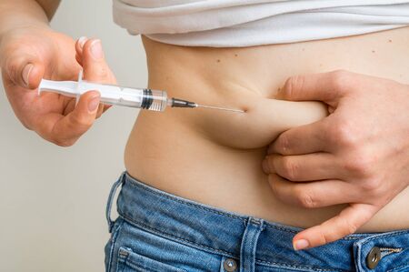 Woman with syringe inject insulin to her belly - diabetes conceptの写真素材