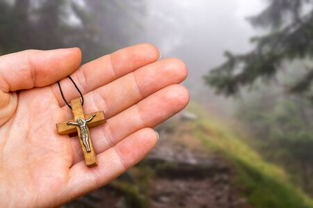 Female hand with wooden cross on haunted forest background - religion conceptの写真素材