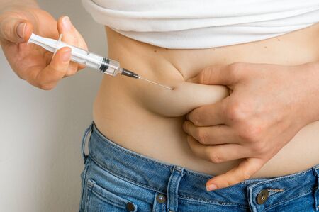 Woman with syringe inject insulin to her belly - diabetes conceptの写真素材