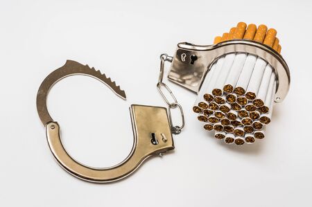 Cigarettes and handcuffs - smoking addiction concept on white backgroundの写真素材