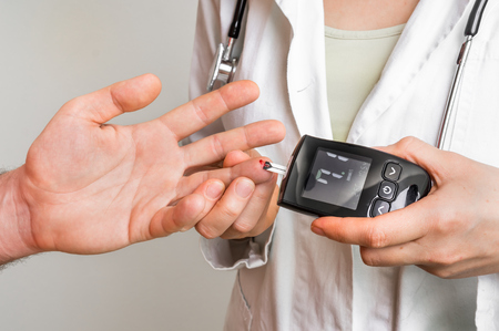 Doctor checking blood sugar level with glucometer - diabetes and glicemia conceptの写真素材