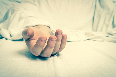 The dead man's body under white cloth with focus on hand in a morgue - retro styleの写真素材