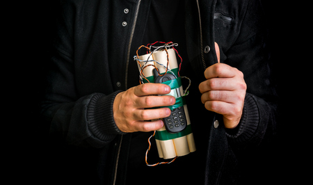 Dangerous terrorist in black jacket with dynamite bomb in hand isolated on black backgroundの写真素材