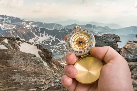 Traveler man with compass seeking a right way in the mountains - navigation conceptの写真素材