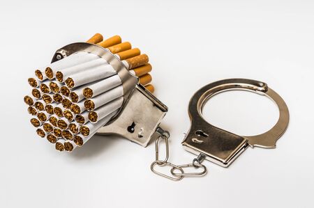Cigarettes and handcuffs - smoking addiction concept on white backgroundの写真素材