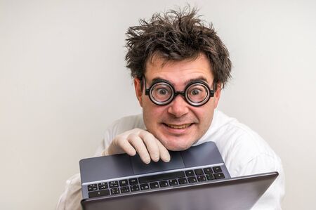 Crazy scientist in glasses with laptop working in his laboratoryの写真素材