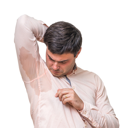 Young man with sweating under armpit in pink shirt isolated on whiteの写真素材
