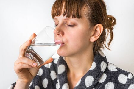 Portrait of young woman drinking water isolated on whiteの写真素材