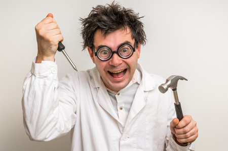 Crazy scientist repairing something with hammer and screwdriverの写真素材