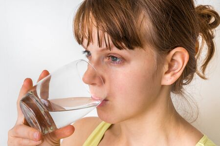 Portrait of young woman drinking water isolated on whiteの写真素材
