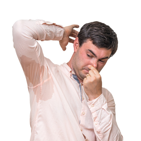 Man with sweating under armpit pinches nose with fingers isolated on whiteの写真素材