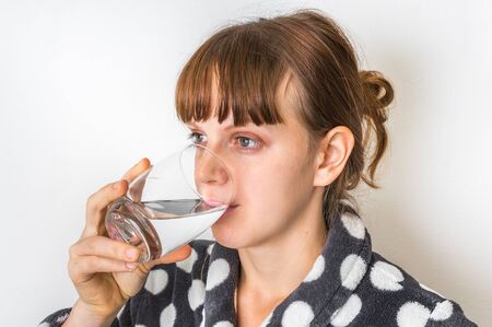 Portrait of young woman drinking water isolated on whiteの写真素材