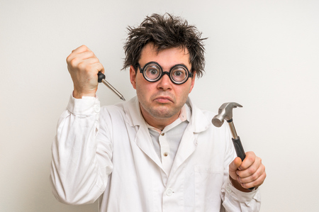 Crazy scientist repairing something with hammer and screwdriverの写真素材