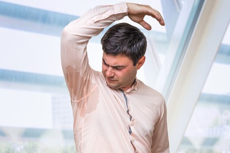 Man with hyperhidrosis sweating under armpit in pink shirtの写真素材