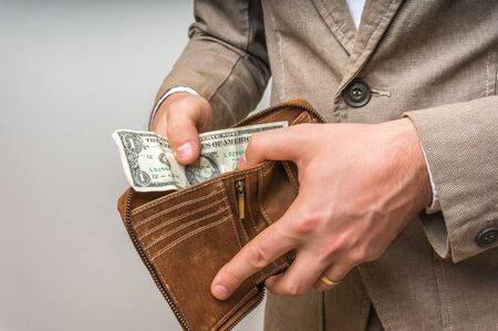 Man holding leather wallet with only one dollar insideの写真素材