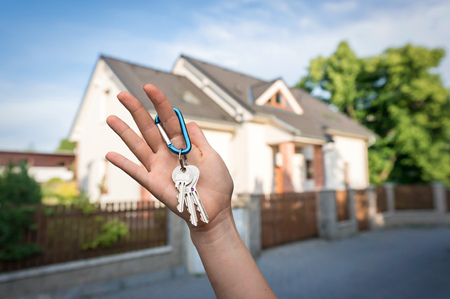 Real estate agent giving house keys to a new property owner on blurred backgroundの写真素材