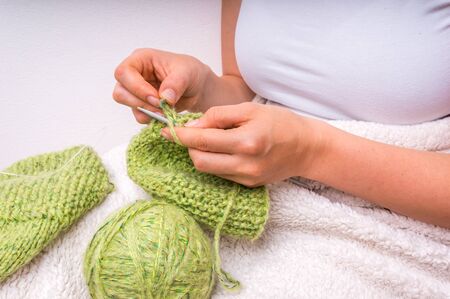 Female hands with needles knitting with green wool at homeの写真素材