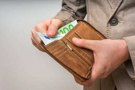 Brown leather wallet with euro money in male handsの写真素材