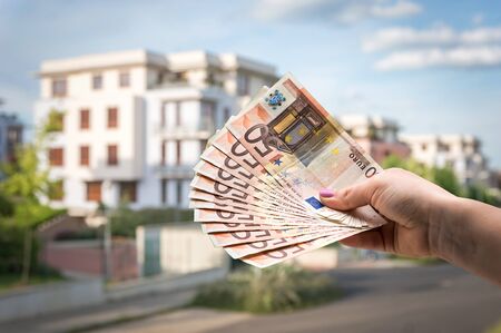 Property buyer holding euro banknotes and buying beautiful house from real estate agencies on blurred backgroundの写真素材