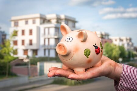 All savings money from pink ceramic piggy bank to pay for the dream home on blurred backgroundの写真素材