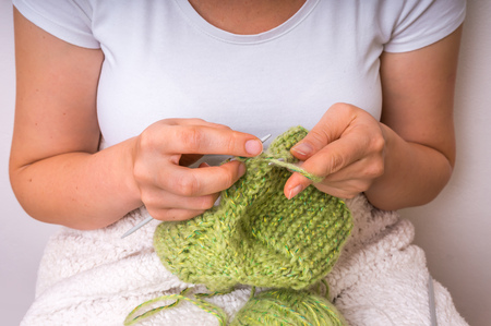 Female hands with needles knitting with green wool at homeの写真素材