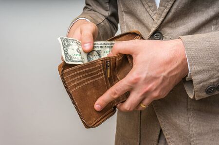 Man holding leather wallet with only one dollar insideの写真素材
