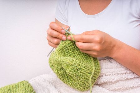 Female hands with needles knitting with green wool at homeの写真素材