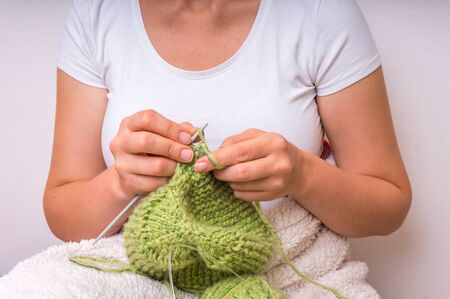 Female hands with needles knitting with green wool at homeの写真素材