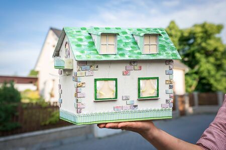 Real estate agent holding model house from paper on blurred backgroundの写真素材