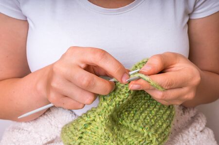 Woman hands with needles knitting with green wool at homeの写真素材