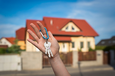 Real estate agent giving house keys to a new property owner on blurred backgroundの写真素材