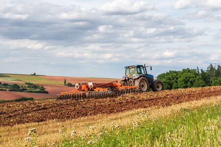 Farmer in blue tractor working on a fieldの写真素材