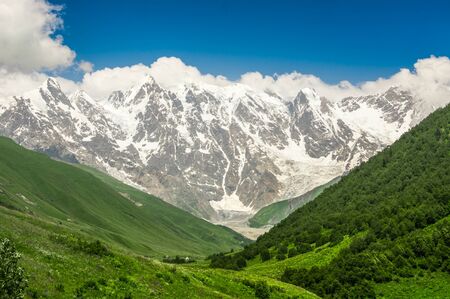 Grassy valley and snow-capped mountains in Georgia (Svaneti)の写真素材