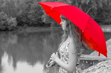 Beautiful young lady with red umbrella near the pondの写真素材