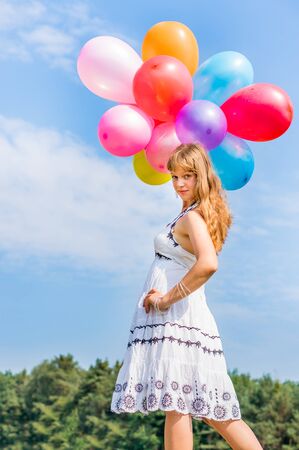 Happy young lady celebrates birthday and playing with balloonsの写真素材
