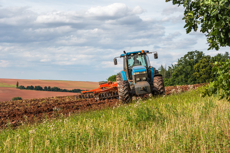 Farmer in blue tractor working on a fieldの写真素材
