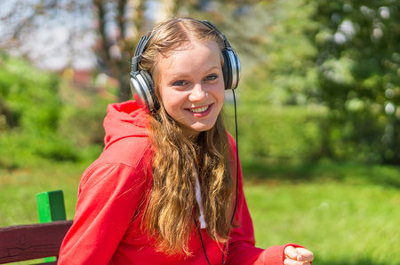 Young lady listening to music and relaxing on a park benchの写真素材