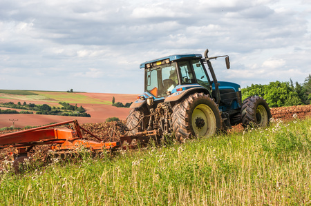 Farmer in blue tractor working on a fieldの写真素材