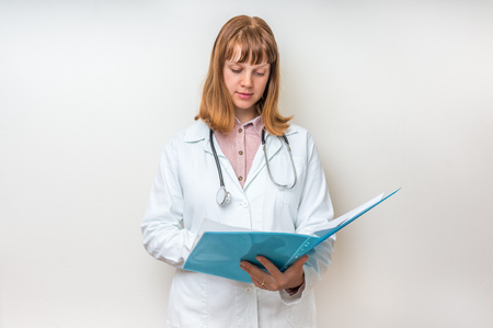 Female doctor holding blue clipboard and reading something about patient diagnosisの写真素材