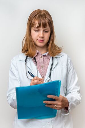 Female doctor with stethoscope writing to clipboard for diagnosis symptom patientの写真素材