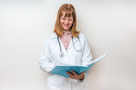 Female doctor holding blue clipboard and reading something about patient diagnosisの写真素材