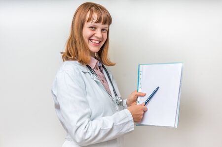 Female doctor showing blank medical clipboard with white paperの写真素材