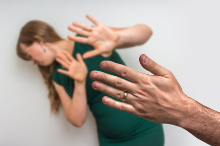 Angry husband is abusing his wife, and woman covering her face - domestic violence conceptの写真素材