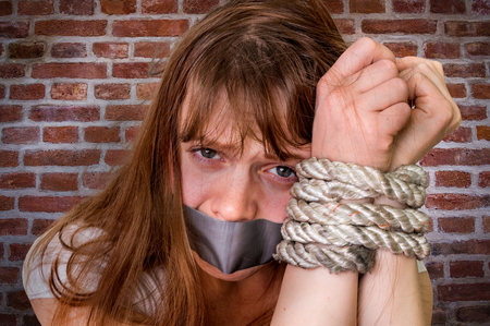 Tied rope hands of kidnapped woman isolated on bricks background - violence conceptの写真素材