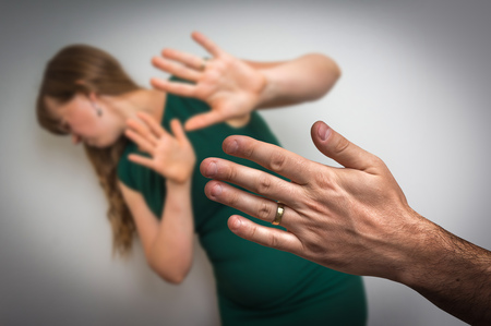 Unhappy wife trying to escape from domestic violence and her husband wants to hit herの写真素材